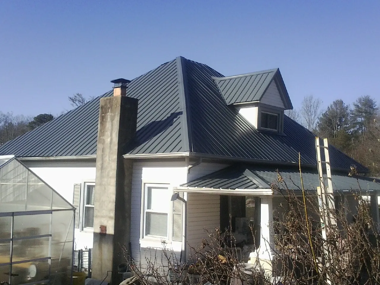 Dark blue standing seam metal roof on a white farmhouse with dormer — Slate & Tile Roof Repair by Roofing Brothers in Chunchula