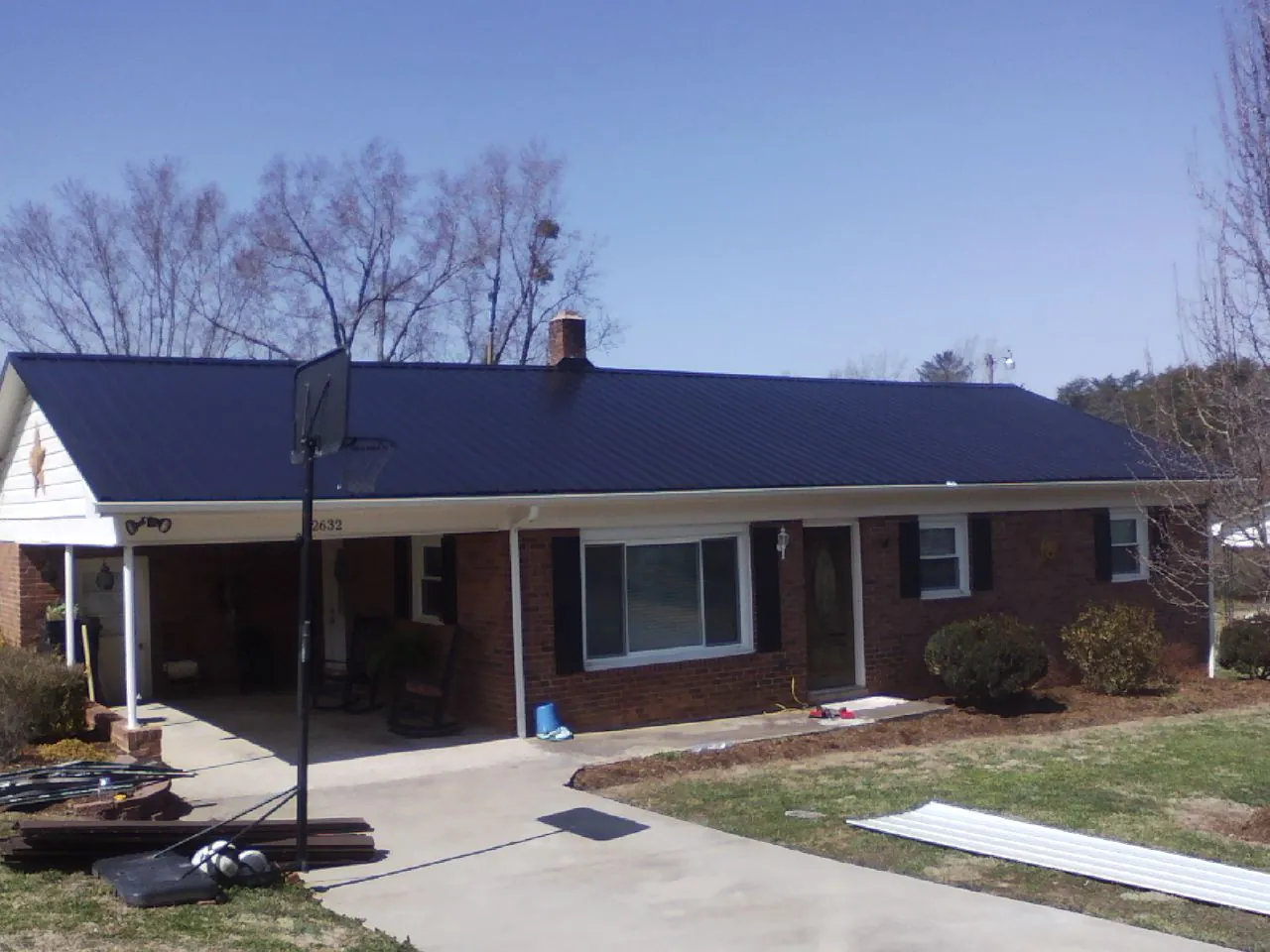 Finished dark blue metal roof on a brick ranch with a carport in Chunchula