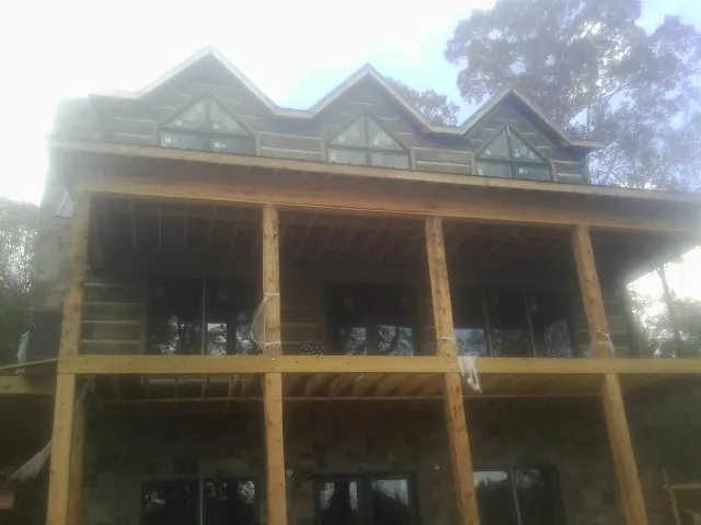 Dormers and porch framing on a large log home under construction — Roof Coating work by our crew in Chunchula
