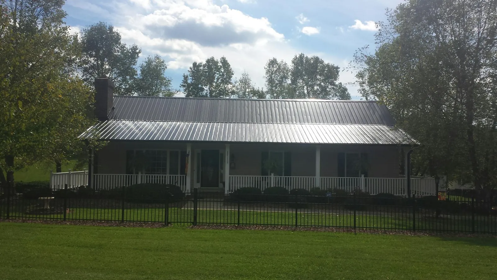 Gray metal roof on a brick ranch with a full width front porch — Gutter Guard Installation work by our crew in Chunchula